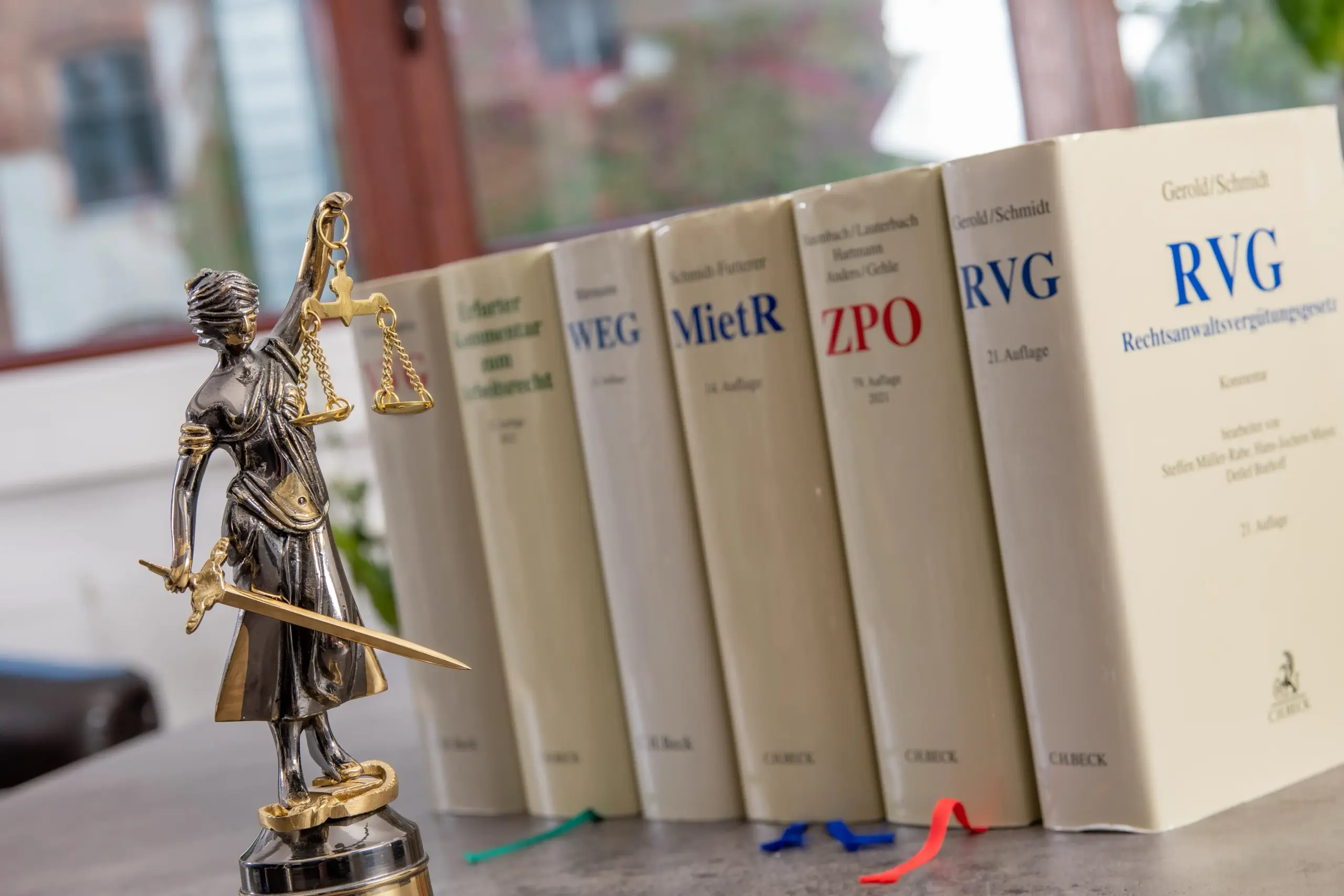 Justitia-Figur vor Gesetzeskommentaren zu RVG, ZPO, Mietrecht und Arbeitsrecht in der Kanzlei Krebs & Behr